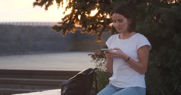 Beautiful Young Woman Typing on Phone Outdoors