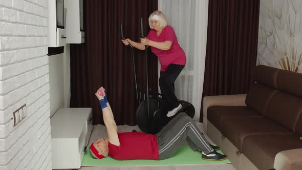 Senior Elderly Couple Using Orbitrek Doing Workout Weight Lifting Sport Dumbbells Exercises at Home