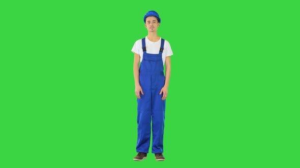Young Construction Worker Smiling on Camera with Hands on His Hips on a Green Screen Chroma Key