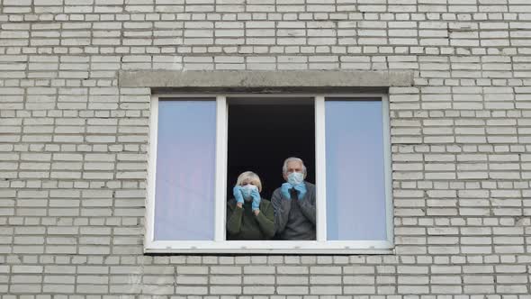 Old Grandparents Stay at Window Isolated at Home on Quarantine. Coronavirus