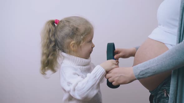 Pregnant Mommy Helps Daughter To Use Headphones in Room