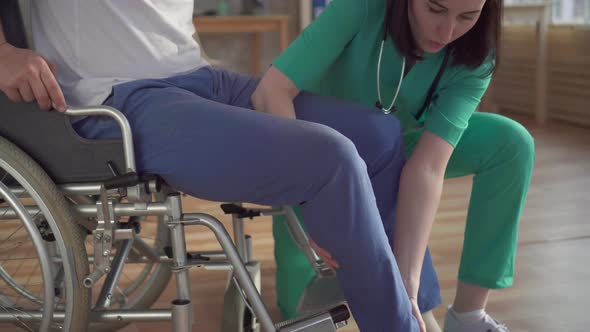 Close Up Girl Nurse Helping a Disabled Person Get Up From a Wheelchair