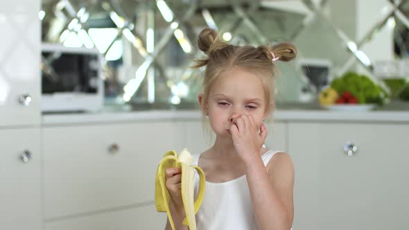 Child Eating Food. Little Girl Eating Banana At Kitchen