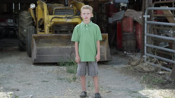 Slow motion push of boy with cleft lip standing in front of tractor.