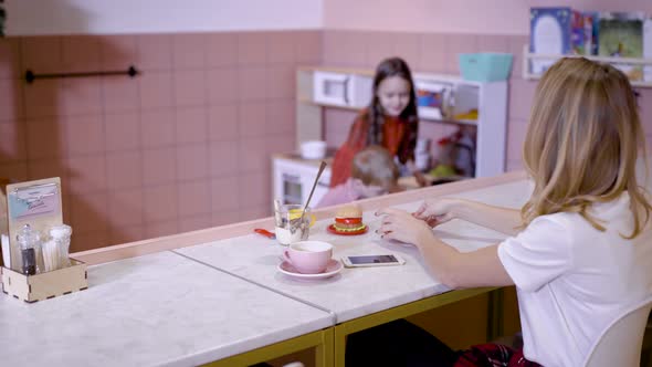 Girl with Mother at Counter in Cafe