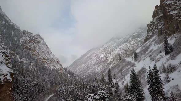 Aerial view flying backwards in snowy canyon