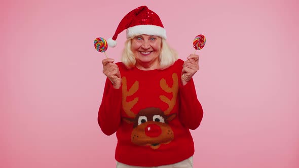 Grandmother in Christmas Sweater Holding Candy Striped Lollipops Hiding Behind Them Fooling Around