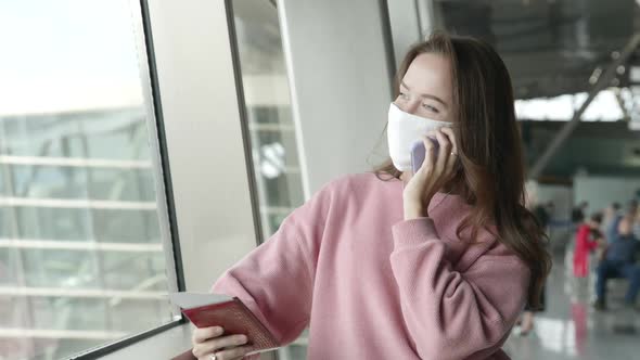 Lonely Girl in Medical Mask in Airport Terminal Talking on Phone with Ticket in Hands Extremely