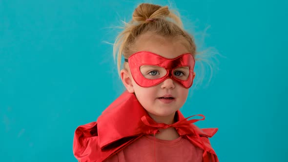 Funny Girl in Red Superhero Costume with Mask Waves Hand