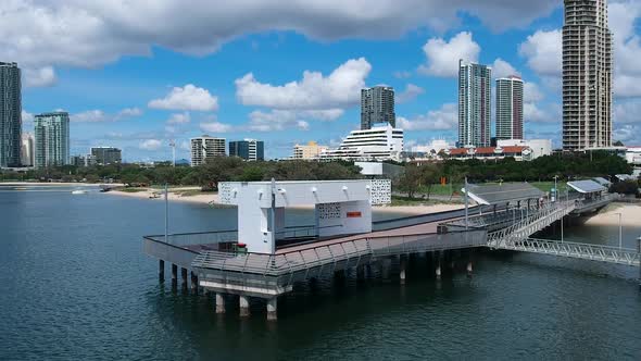 Revealing aerial video of a city wharf and boat jetty located close to a park and high-rise building
