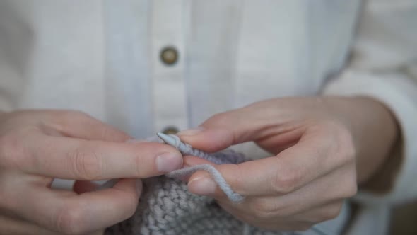 Hands of a woman knitting needles.