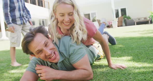 Happy caucasian couple with son playing and lying in garden