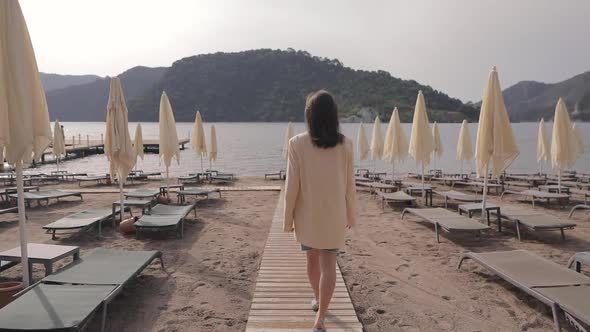 Brunette woman walking on empty beach due to COVID-19