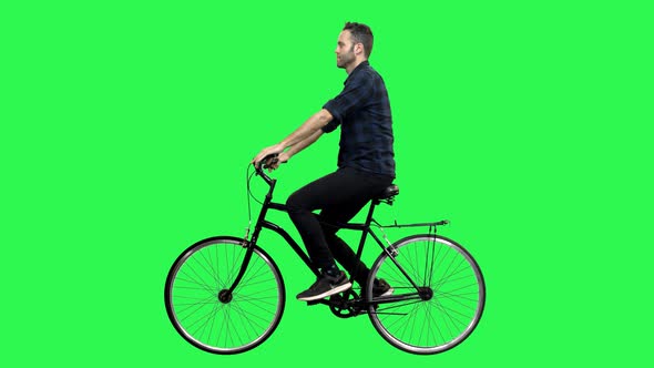 A Cute man riding a bicycle over a green screen, looking around and upwards.4K