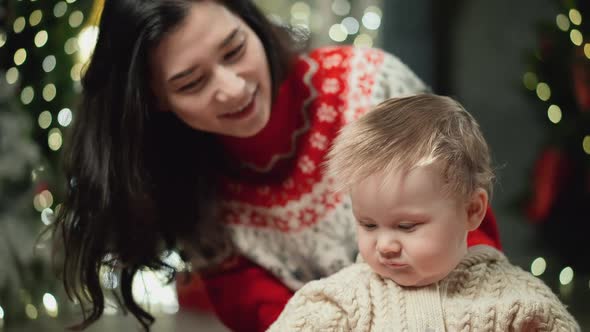 Mom and Baby are Looking at a Red Christmas Hat