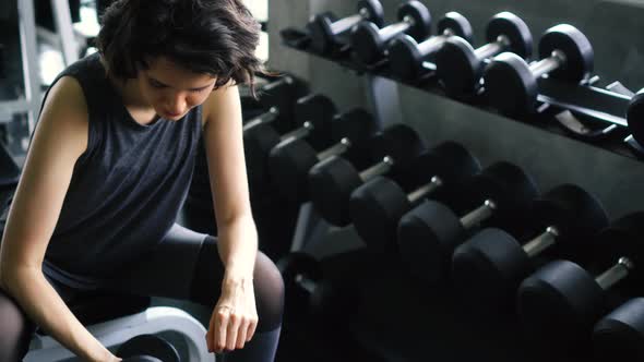 Young Woman in Sportswear Doing Seated Dumbbell Concentration Curl Bicep Exercise at the Gym