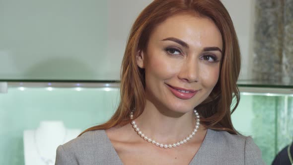 Gorgeous Happy Woman Trying on a Pearl Necklace