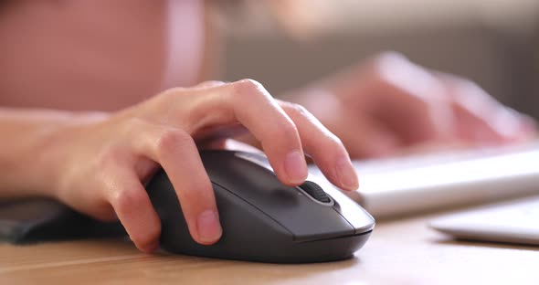 Hands typing on computer keyboard and use of mouse in office