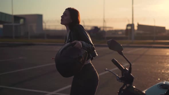 Beautiful Young Redhaired Woman Motorcyclist Dancing Next to Her Custom Bike with Black Motorcycle