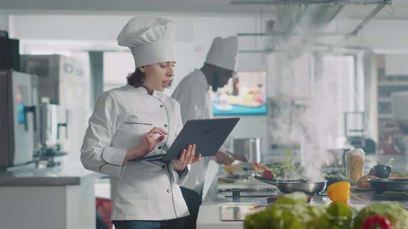 Female Cook Looking at Laptop Screen to Follow Food Recipe