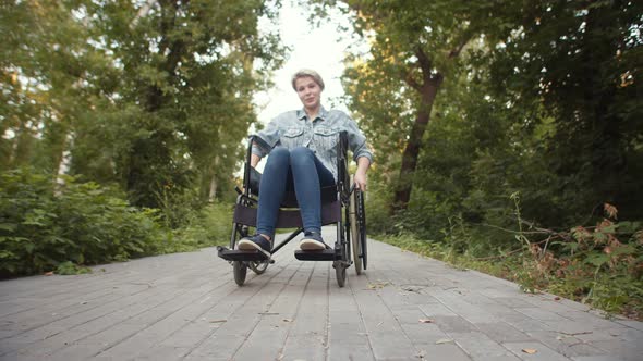 Happy Disabled Woman is Sitting in Wheelchair in Park Rotation