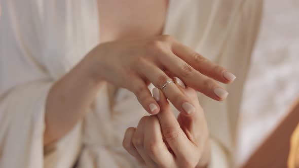 Bride in night gown, veil wearing engagement ring near window, Close-up, Wedding morning