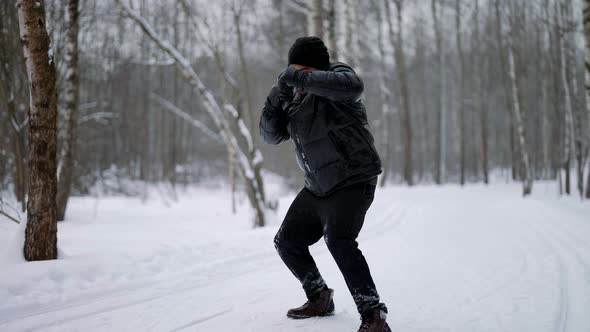 Professional MMA Fighter Punches on the Background of Nature in Winter in Snowy Weather