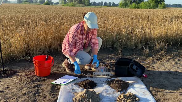 Female Scientist Testing Soil Sample Outdoors Using Lab Equipment