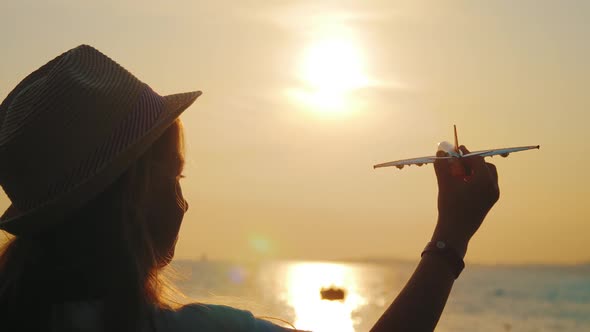 Silhouette Young Girl Plays with a Toy Airplane on Sunset