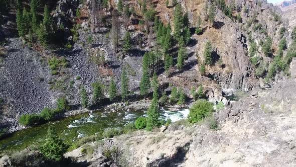 Aerial view of a river flowing fast at the bottom of a steep canyon in the Rocky Mountains