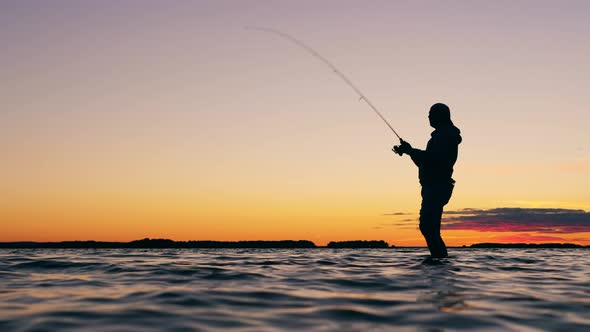 A Man Is Getting a Fish From the Lake with a Fishing Rod