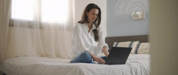 A young woman smiling while working on her computer from home.