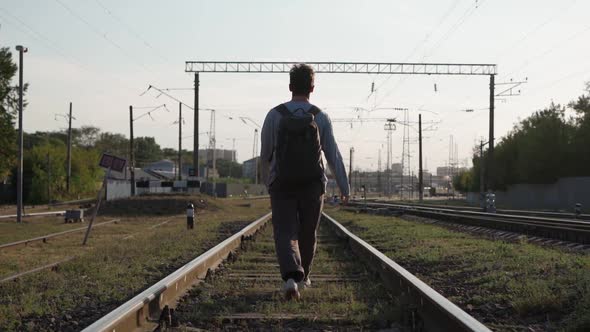 Man Walks Along the Train Tracks and Raises His Hands Up Feeling Freedom