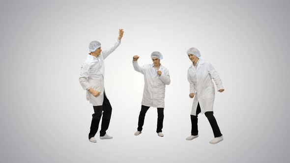 Three Male Doctors in White Robes and Protective Caps Doing Funny Celebration Dance on Gradient