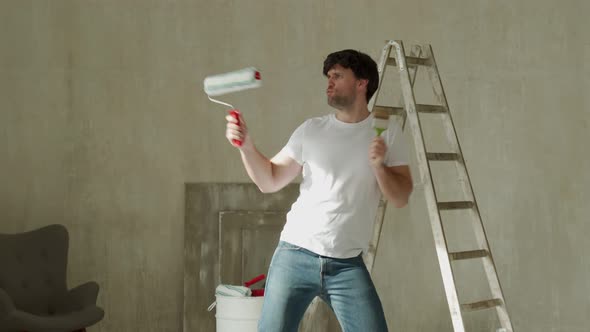 Funny Man with a Brush and Roller Dances Moves and Sings During the Renovation of the House