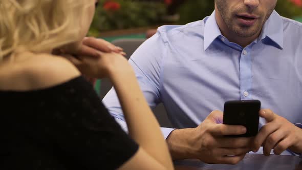 Man Using Mobile Phone at Table While Woman Talking to Him, Irritation, Crisis