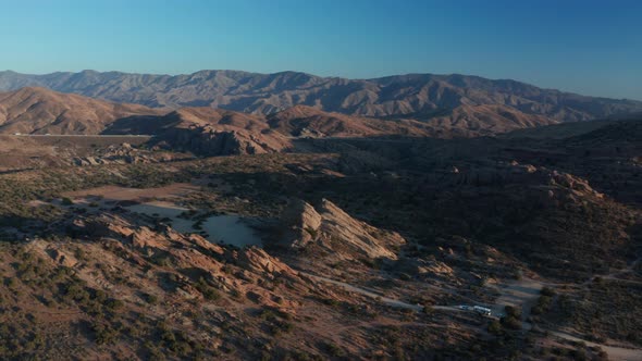 Desert landscape - Aerial footage of mountains and dry land with blue cloudy sky in the background.