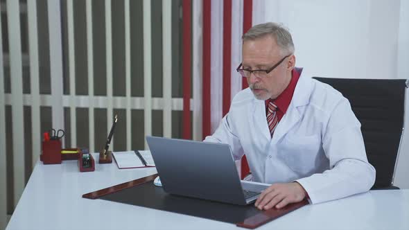 Older doctor making video call on laptop.