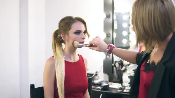 Makeup Artist Using Big Brush to Apply Face Powder and Finishing Make Up for a Young Blonde Woman in