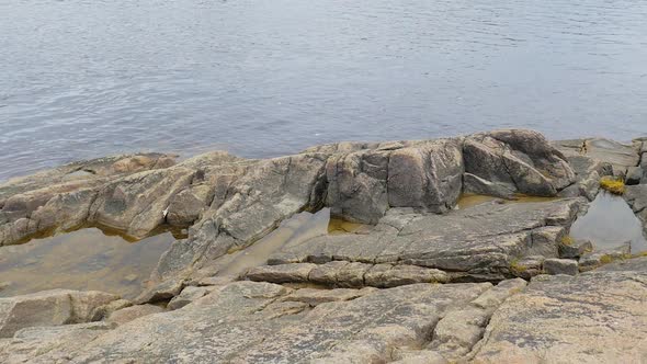 Large Rocks Along The Shore Showing More Rocks In The Water