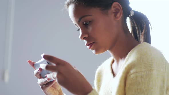 Meditative African girl texting by phone