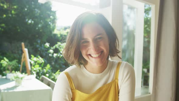 Portrait of smiling caucasian woman with brown hair at home on sunny day