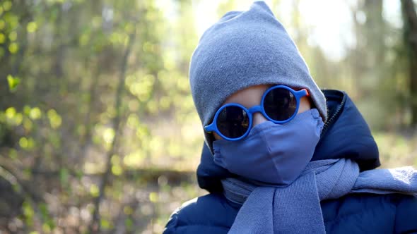 Boy Walks in a Mask Protected From the Virus and Colorful Round Glasses