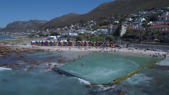 Drone rises to reveals beautiful and historically coloured beach huts of St James beach and the ocea