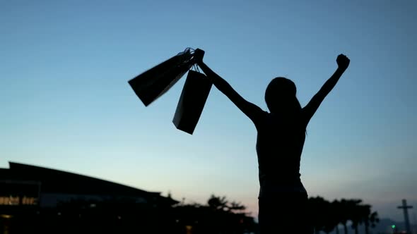 Slow Motion of Woman Raising up Shopping Bag Under Sunset 