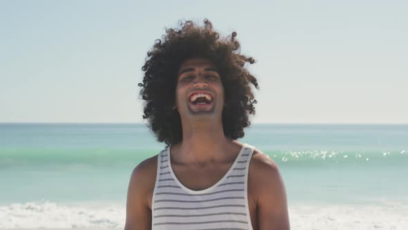 Mixed race man looking at the camera and laughing at beach