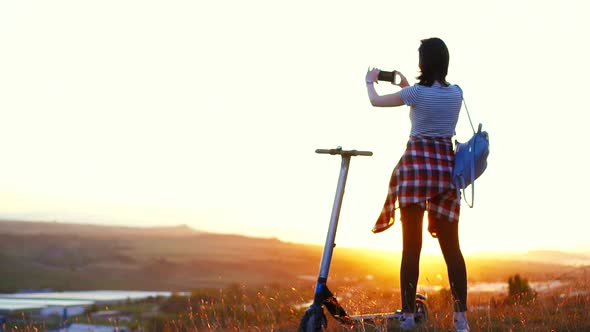 Girl Stands Next To the Electric Scooter Taking Pictures of the Mountain Landscape and Sunsetslow Mo