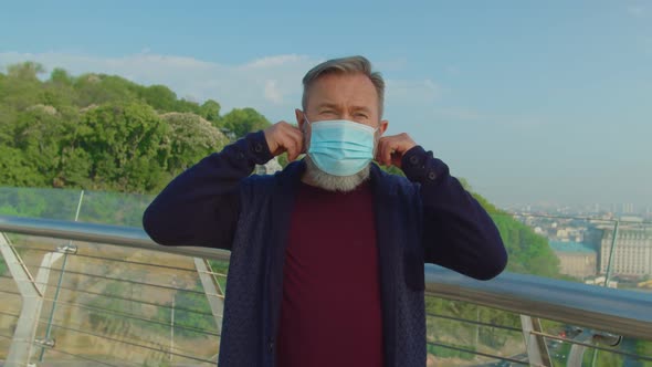 Senior Man Putting Off Medical Mask and Taking Deep Breath Outdoors