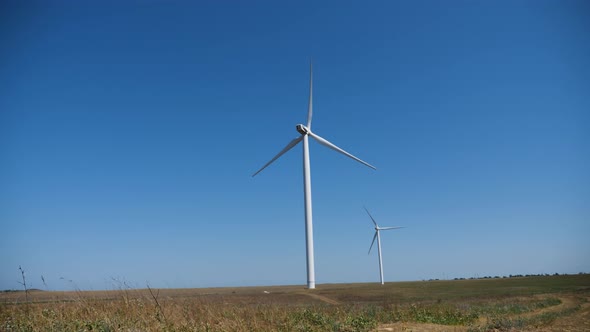 Working Twisting Windmills Stand in a Field in Summer