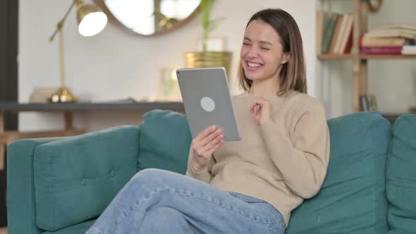 Video Chat on Tablet By Young Woman on Sofa